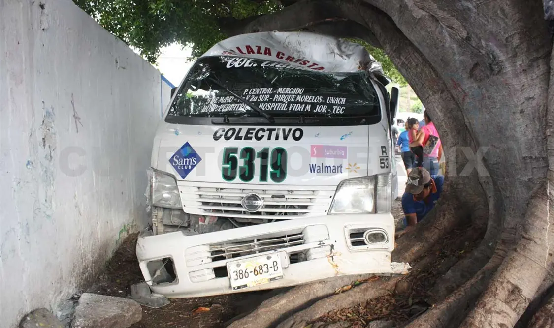 Colectivo queda atrapado entre barda y árbol