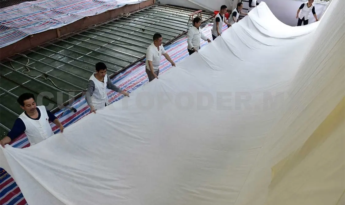 Trabajadores chinos estiran el papel Xuan, que mide 11 metros de longitud y 3.3 metros de anchura y es elaborado para pintura tradicional a gran escala. Cortesía