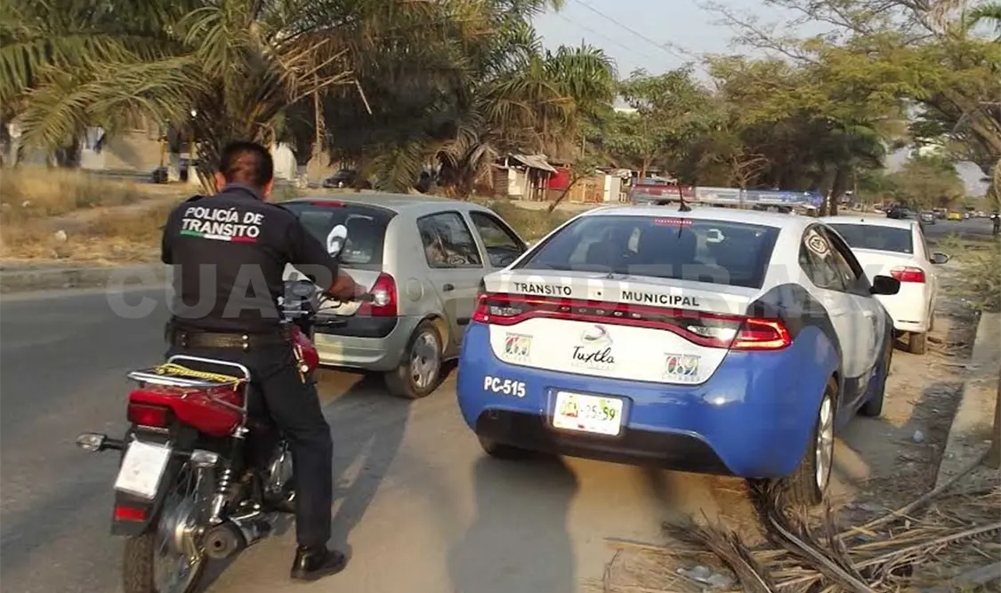 El agente de Tránsito Municipal conduce la moto accidentada, mientras su compañero lo escolta con la patrulla. A. Alegría / CP