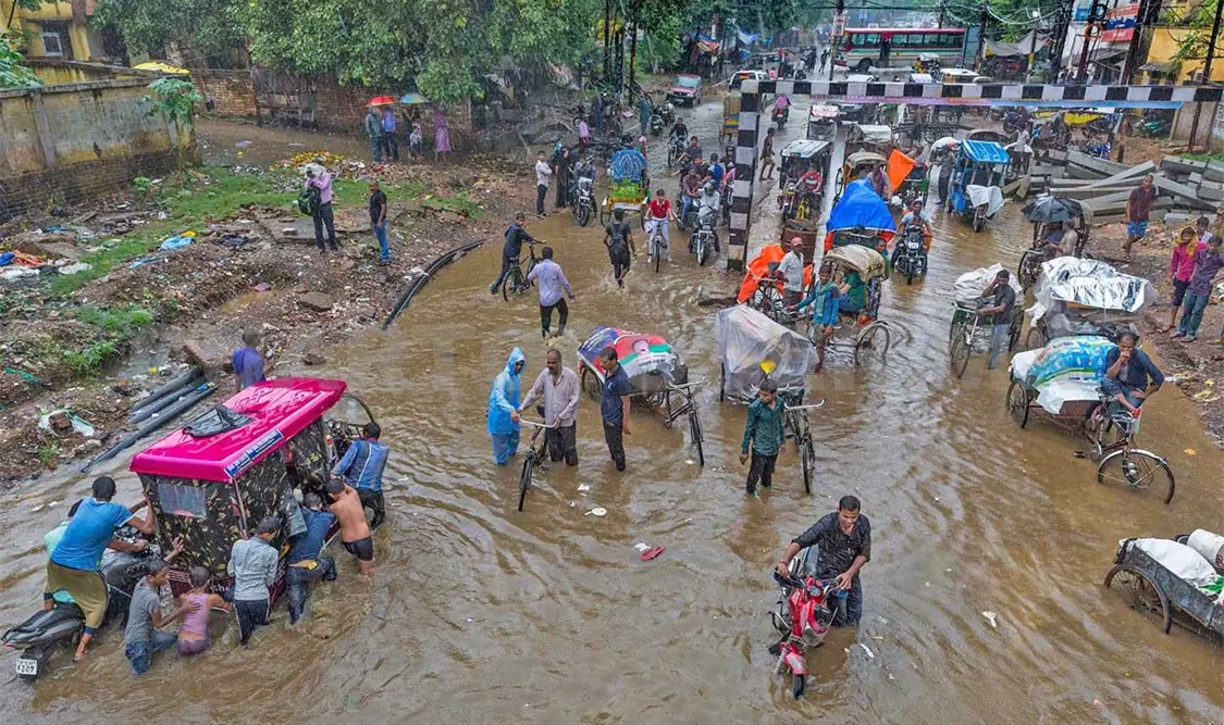 La panorámica muestra a gente caminando sobre calles inundadas en una zona del estado de Kerala. AP