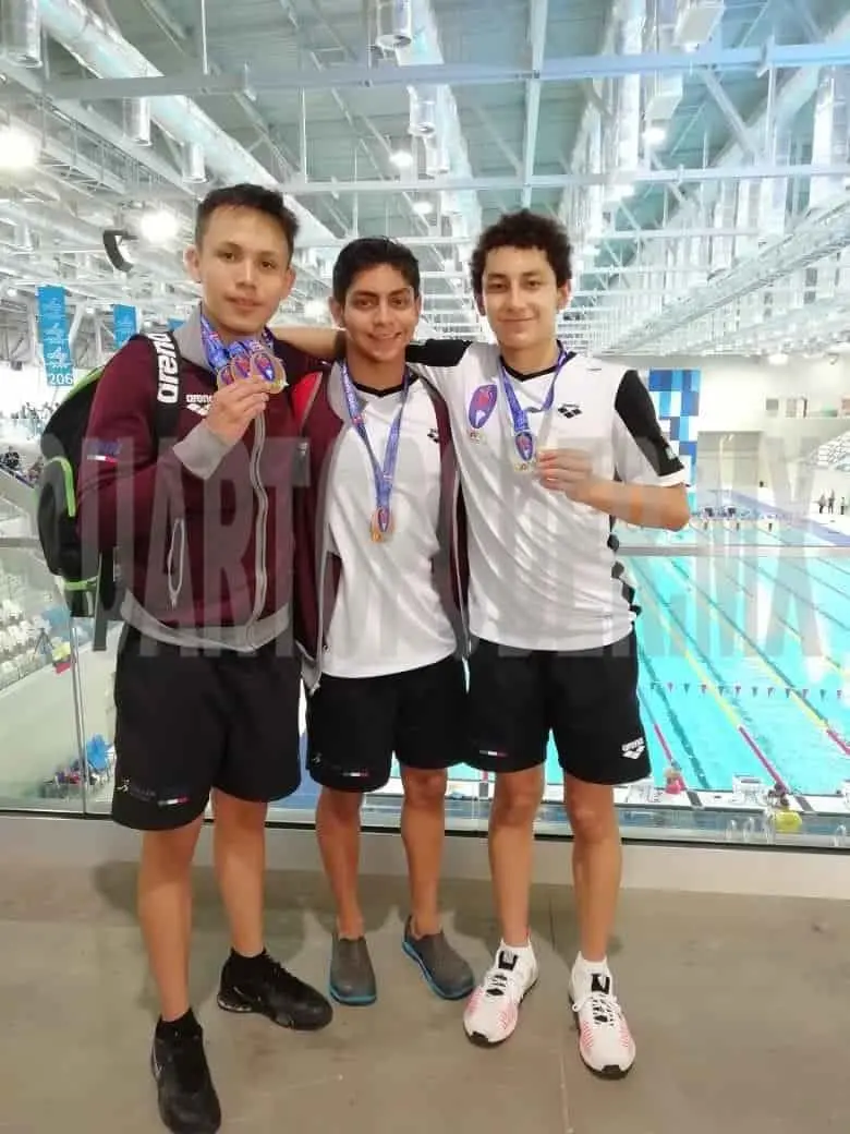 En medio, el nadador chiapaneco presume la medalla que consiguió en el evento peruano. Cortesía