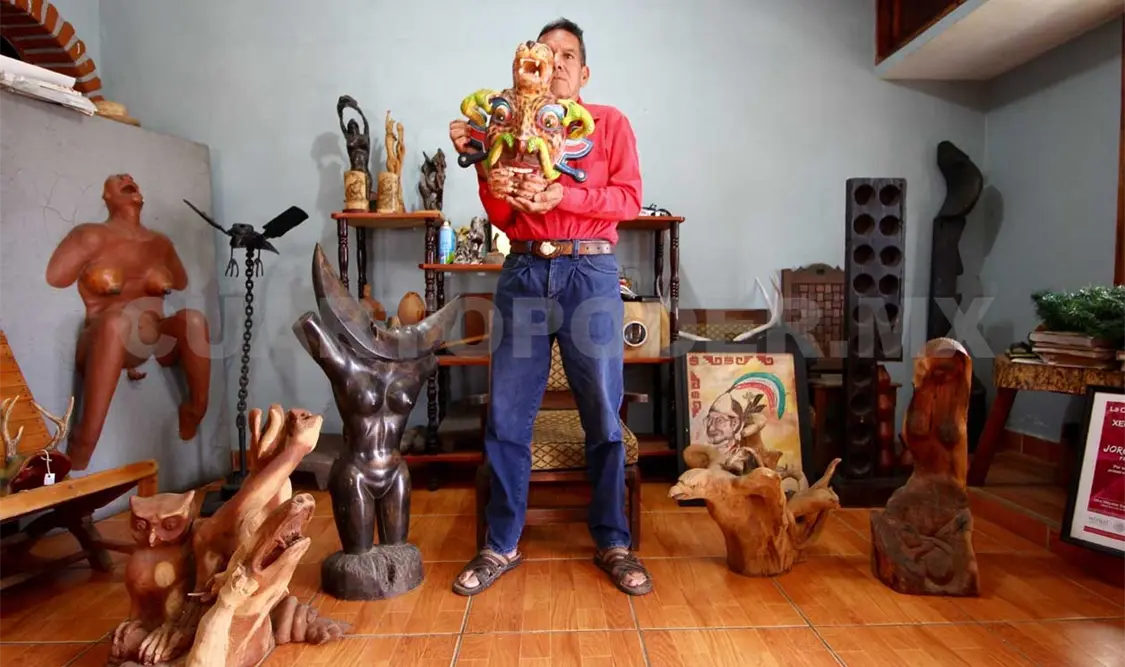Jorge García sujeta una de sus máscaras y en su entorno muestra algunas de sus piezas de arte-objeto que elabora.