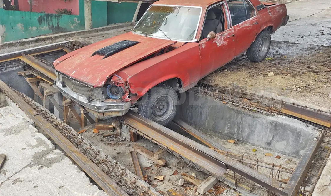 Cae Chevy Nova en alcantarilla y termina atascado