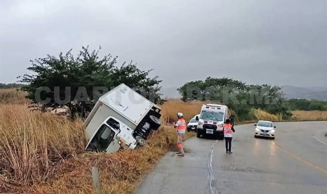 Vuelca camión por lluvia y queda en la maleza