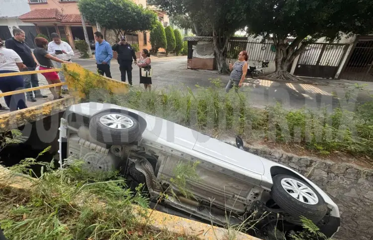 Cae sedán al fondo de canal de aguas residuales