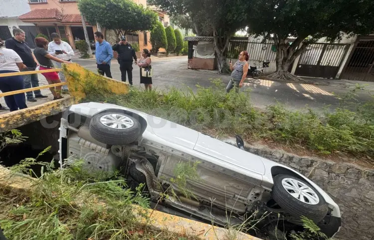 Cae sedán al fondo de canal de aguas residuales