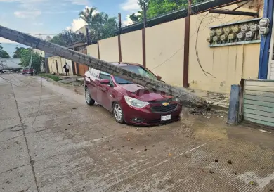 Tráiler derriba poste y cae en vehículo aparcado