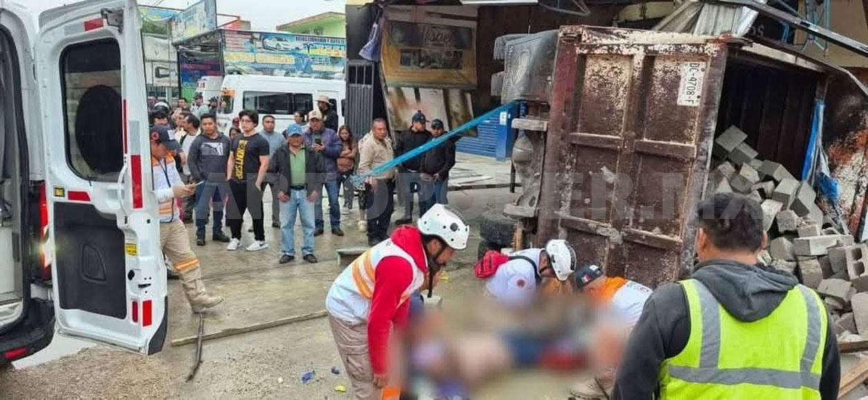 Mujer queda atrapada bajo la caja de un volteo